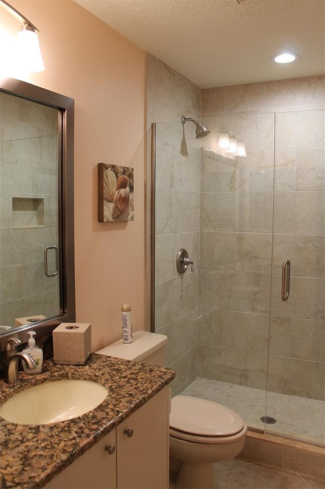 bathroom featuring toilet, tile patterned flooring, a shower with shower door, vanity, and a textured ceiling