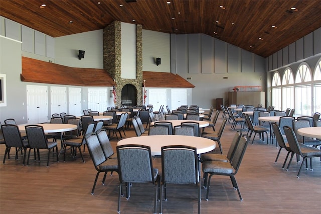 dining room featuring a stone fireplace, wooden ceiling, high vaulted ceiling, and wood-type flooring