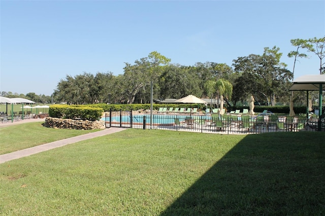 view of property's community featuring a lawn and a swimming pool