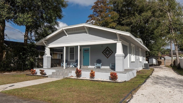 bungalow featuring covered porch, a front yard, and cooling unit