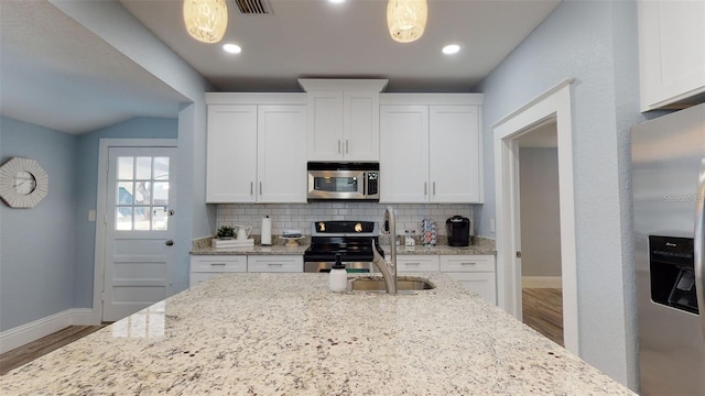 kitchen with stainless steel appliances, light stone countertops, and white cabinets