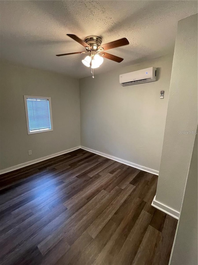 unfurnished room featuring an AC wall unit, dark wood-type flooring, a textured ceiling, and ceiling fan