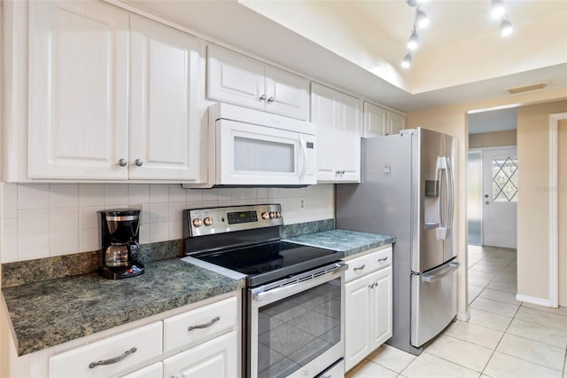 kitchen with white cabinetry, stainless steel appliances, light tile patterned flooring, and backsplash