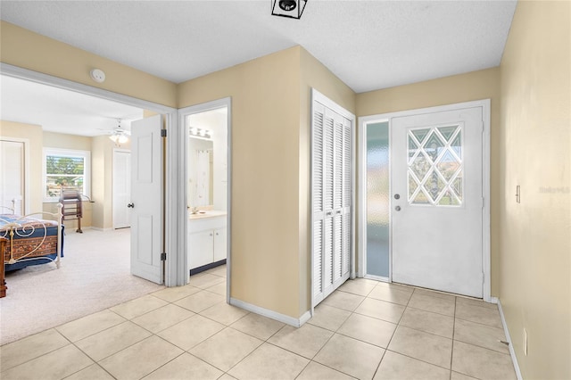 foyer with a textured ceiling, ceiling fan, and light tile patterned floors