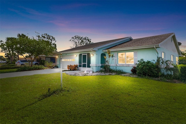 ranch-style home with a garage and a yard