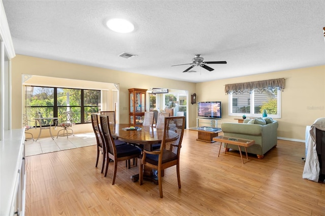 dining room with a wealth of natural light, ceiling fan, a textured ceiling, and light hardwood / wood-style flooring