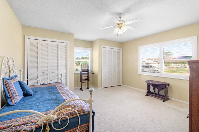 bedroom with multiple windows, a textured ceiling, two closets, and ceiling fan