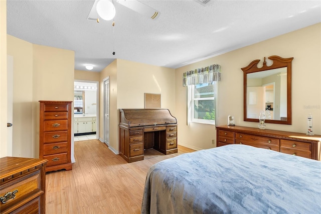 bedroom with light wood-type flooring, a textured ceiling, ceiling fan, and ensuite bathroom