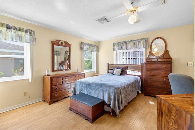 bedroom with light wood-type flooring, a textured ceiling, and ceiling fan