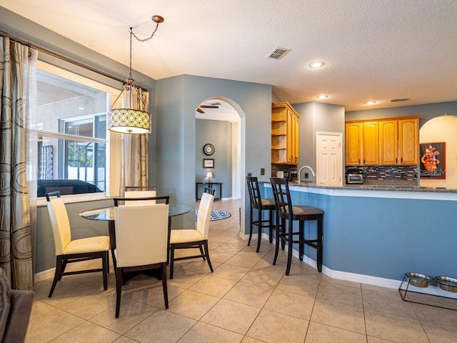 dining space with light tile patterned floors, a textured ceiling, and sink