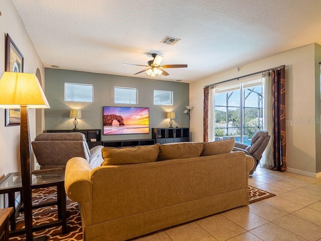 living room featuring ceiling fan, light tile patterned flooring, and a textured ceiling