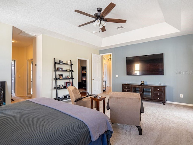 carpeted bedroom featuring a textured ceiling, a tray ceiling, and ceiling fan