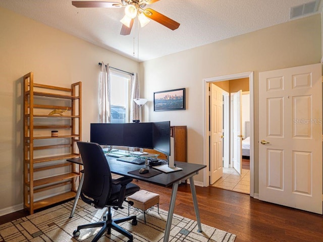 office area with ceiling fan, dark hardwood / wood-style flooring, and a textured ceiling