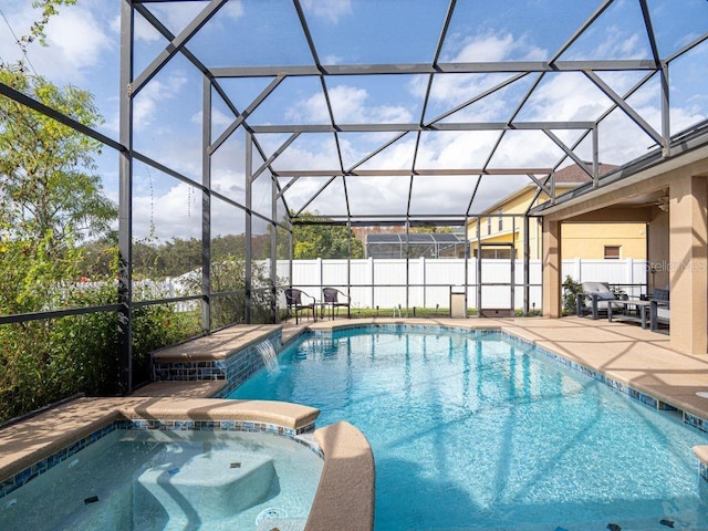 view of pool featuring glass enclosure, an in ground hot tub, and a patio