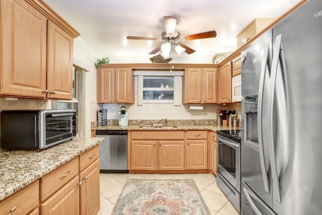 kitchen featuring light stone counters, light tile patterned floors, appliances with stainless steel finishes, ceiling fan, and sink