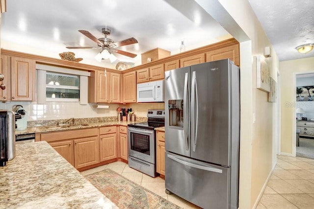 kitchen with appliances with stainless steel finishes, sink, ceiling fan, light stone counters, and light tile patterned floors