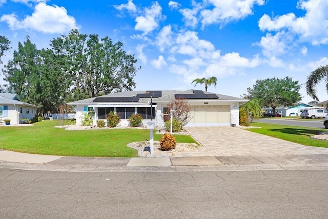 view of front of house featuring solar panels, a front lawn, and a garage