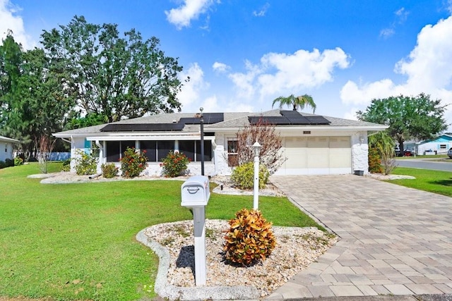 single story home featuring solar panels, a front yard, a garage, and a sunroom