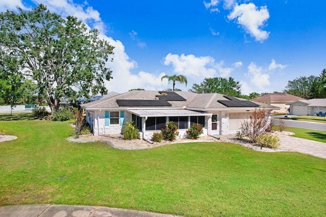 view of front of home with a front yard, a garage, and solar panels