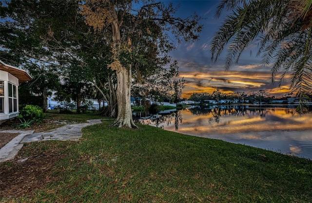 yard at dusk featuring a water view