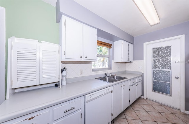 kitchen with tasteful backsplash, sink, light tile patterned flooring, white dishwasher, and white cabinetry