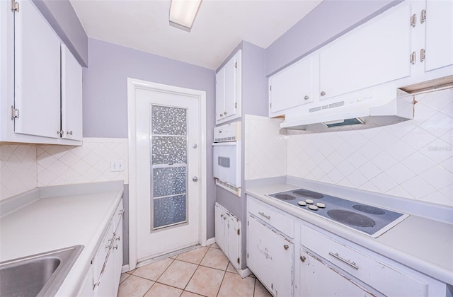 kitchen with white cabinets, tasteful backsplash, light tile patterned flooring, sink, and white appliances