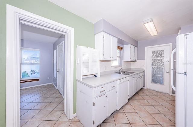 kitchen with white appliances, light tile patterned floors, sink, and white cabinets