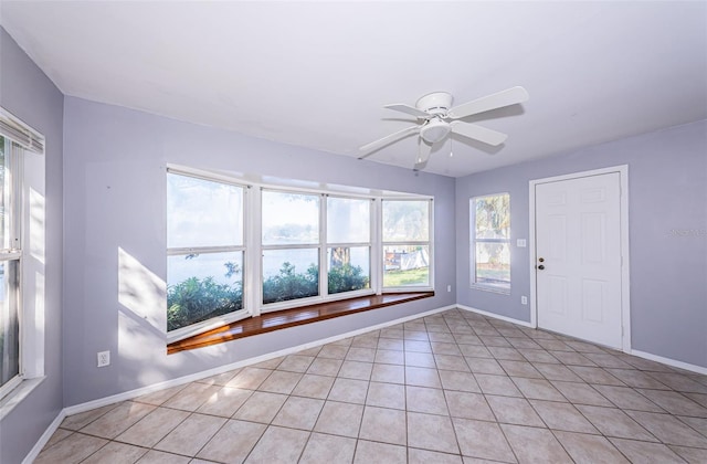 interior space featuring baseboards, a ceiling fan, and light tile patterned flooring