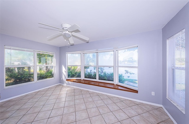 unfurnished room featuring baseboards, ceiling fan, plenty of natural light, and light tile patterned floors