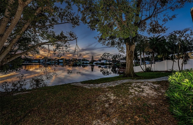 yard at dusk featuring a water view