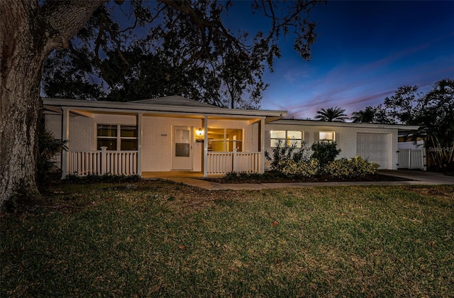 ranch-style house featuring covered porch, brick siding, a front lawn, and a garage