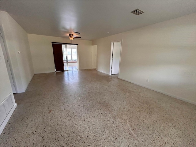empty room featuring baseboards, visible vents, and speckled floor