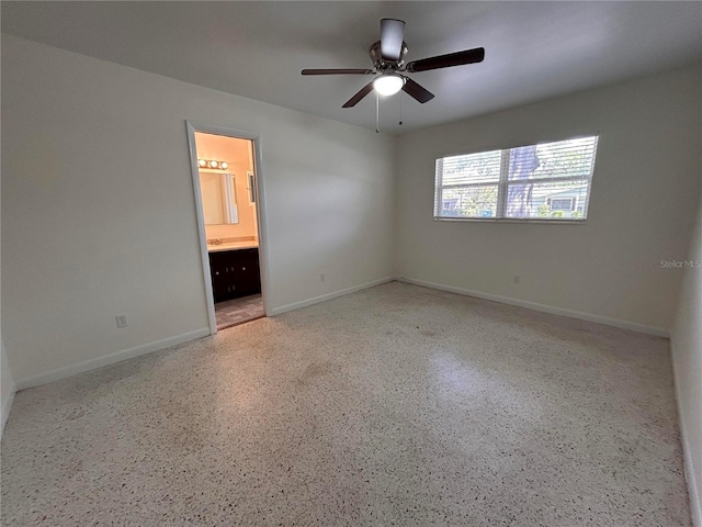 empty room featuring baseboards, speckled floor, and ceiling fan