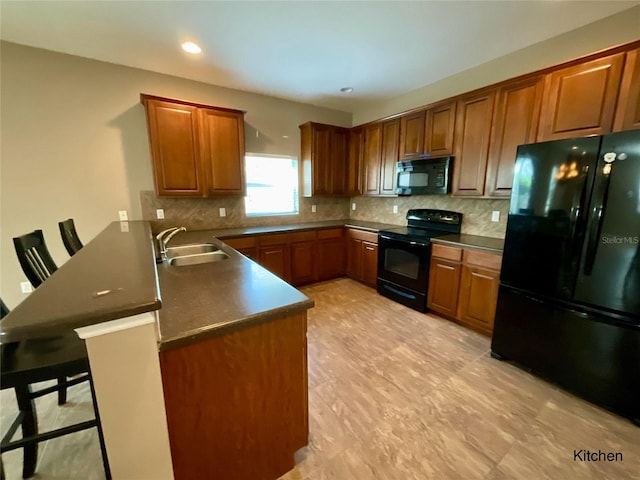 kitchen with kitchen peninsula, backsplash, a kitchen bar, black appliances, and sink