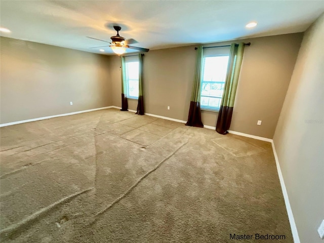 carpeted spare room featuring a wealth of natural light and ceiling fan