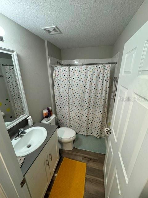 bathroom with vanity, hardwood / wood-style floors, toilet, and a textured ceiling