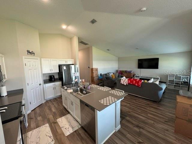 kitchen with lofted ceiling, white cabinets, a kitchen island with sink, dark wood-type flooring, and stainless steel appliances