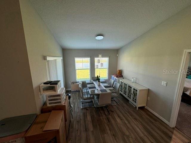 dining area with dark wood-type flooring and a textured ceiling