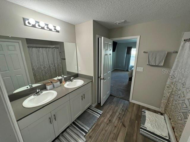 bathroom with vanity, a textured ceiling, hardwood / wood-style flooring, and walk in shower