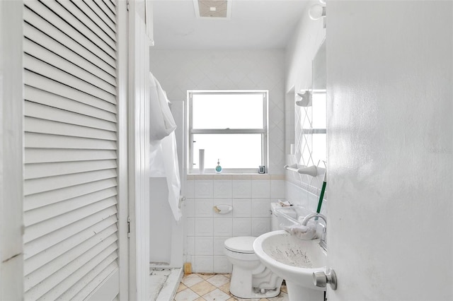 bathroom featuring tile patterned flooring, sink, tile walls, and toilet