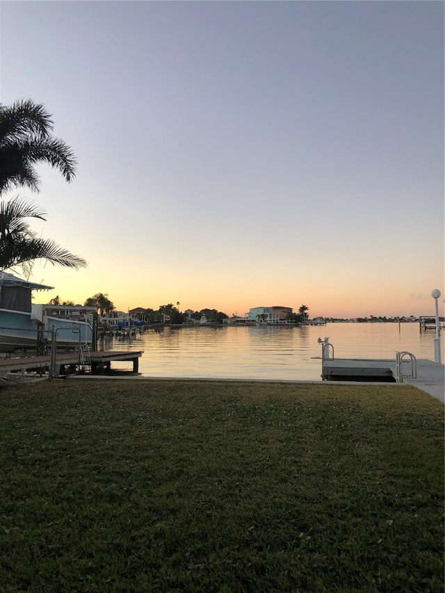 dock area with a lawn and a water view