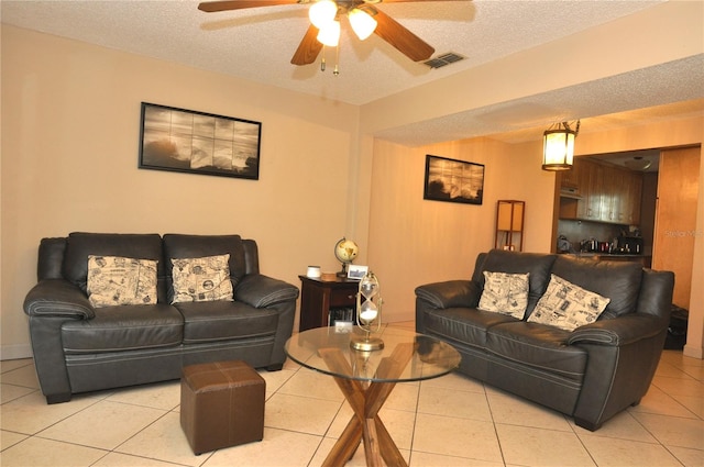 living room featuring ceiling fan, a textured ceiling, and light tile patterned floors