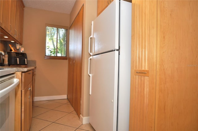 kitchen featuring stove, light tile patterned floors, a textured ceiling, and white refrigerator