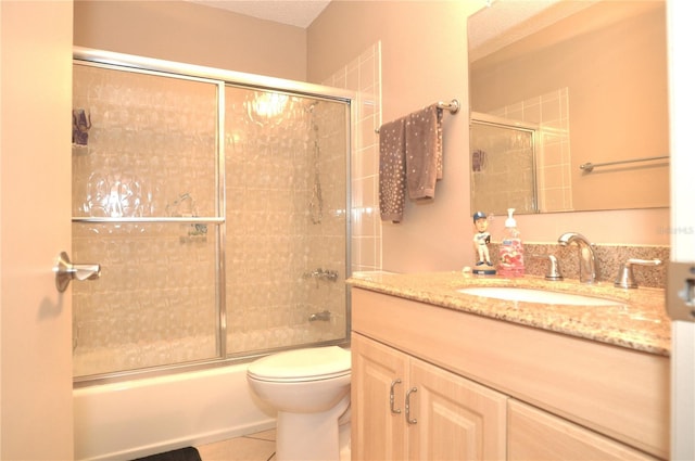 full bathroom featuring tile patterned flooring, vanity, shower / bath combination with glass door, and toilet