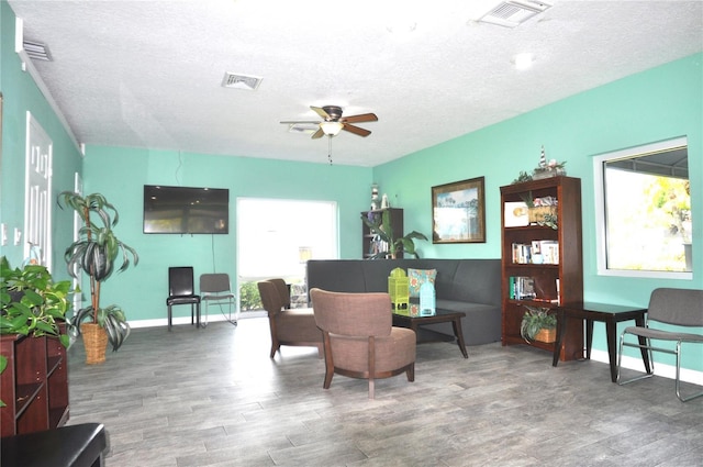 living area featuring a textured ceiling, wood-type flooring, and ceiling fan