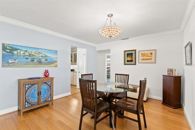 dining space featuring light hardwood / wood-style floors and ornamental molding