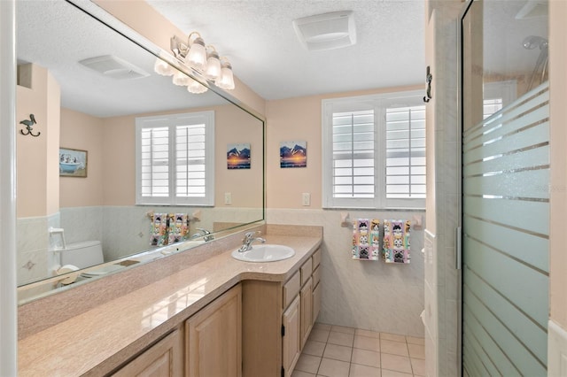 bathroom with tile patterned floors, vanity, tile walls, a chandelier, and toilet