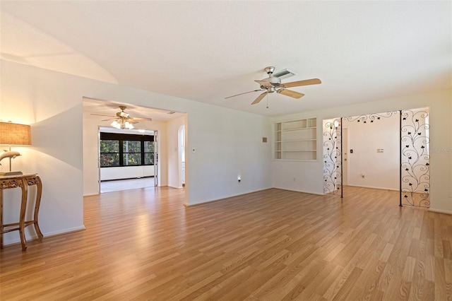 unfurnished living room featuring built in shelves, light wood-type flooring, and ceiling fan