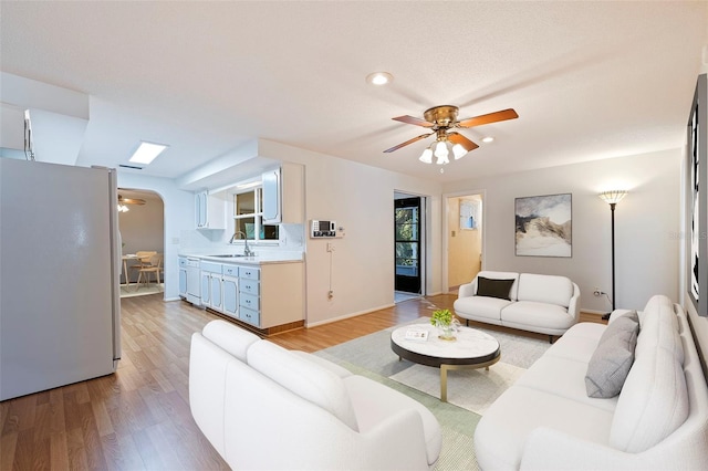 living room with light hardwood / wood-style flooring, sink, and ceiling fan