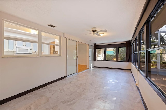 unfurnished sunroom featuring ceiling fan and a wealth of natural light